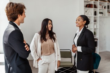Three employees, standing, talking in office