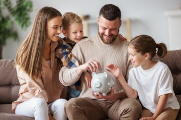 Family saving money, putting coins in piggy bank