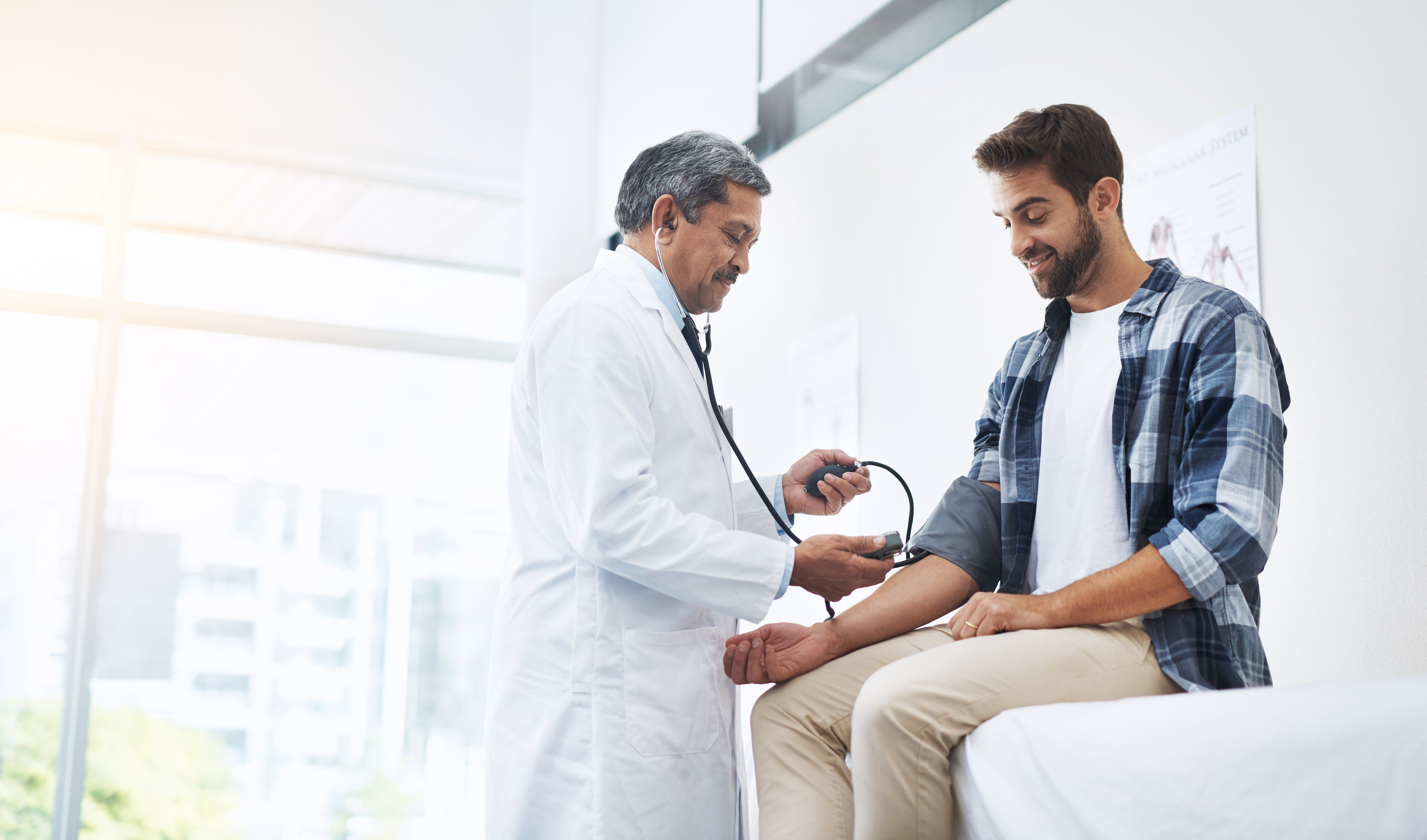 Young man being examined by doctor, getting blood pressure taken