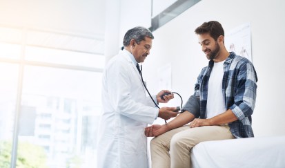 Young man being examined by doctor, getting blood pressure taken