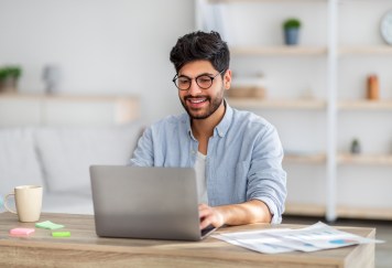 Man sitting at desk, working on computer, smiling