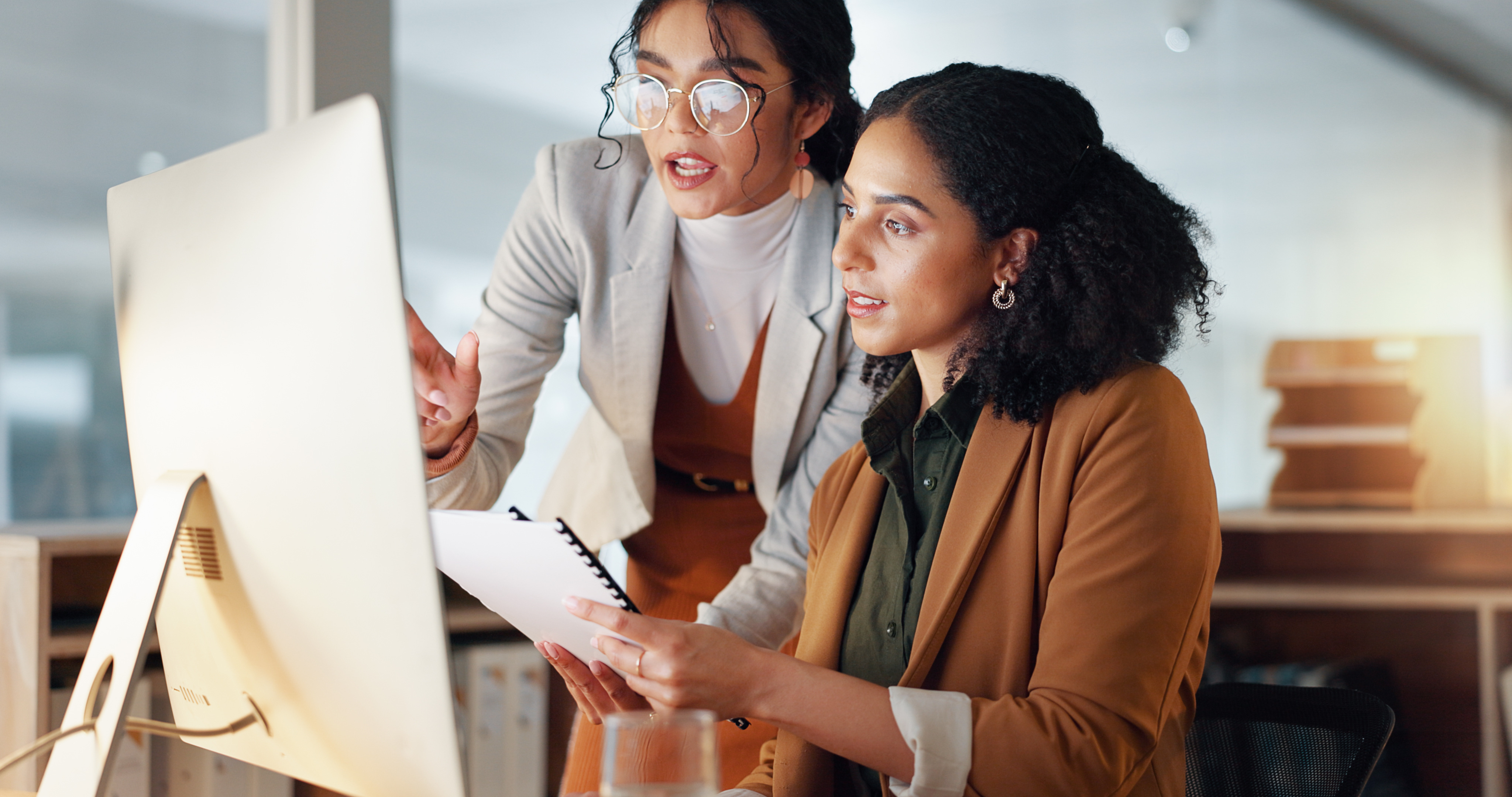 Two women working together, looking at computer
