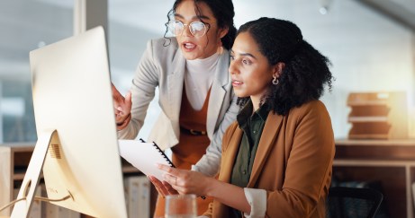 Two women working together, looking at computer