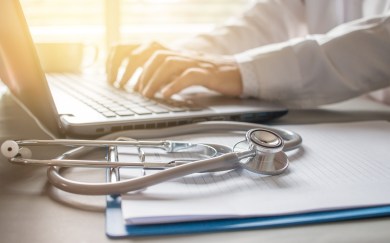 A medical professional types on a keyboard.