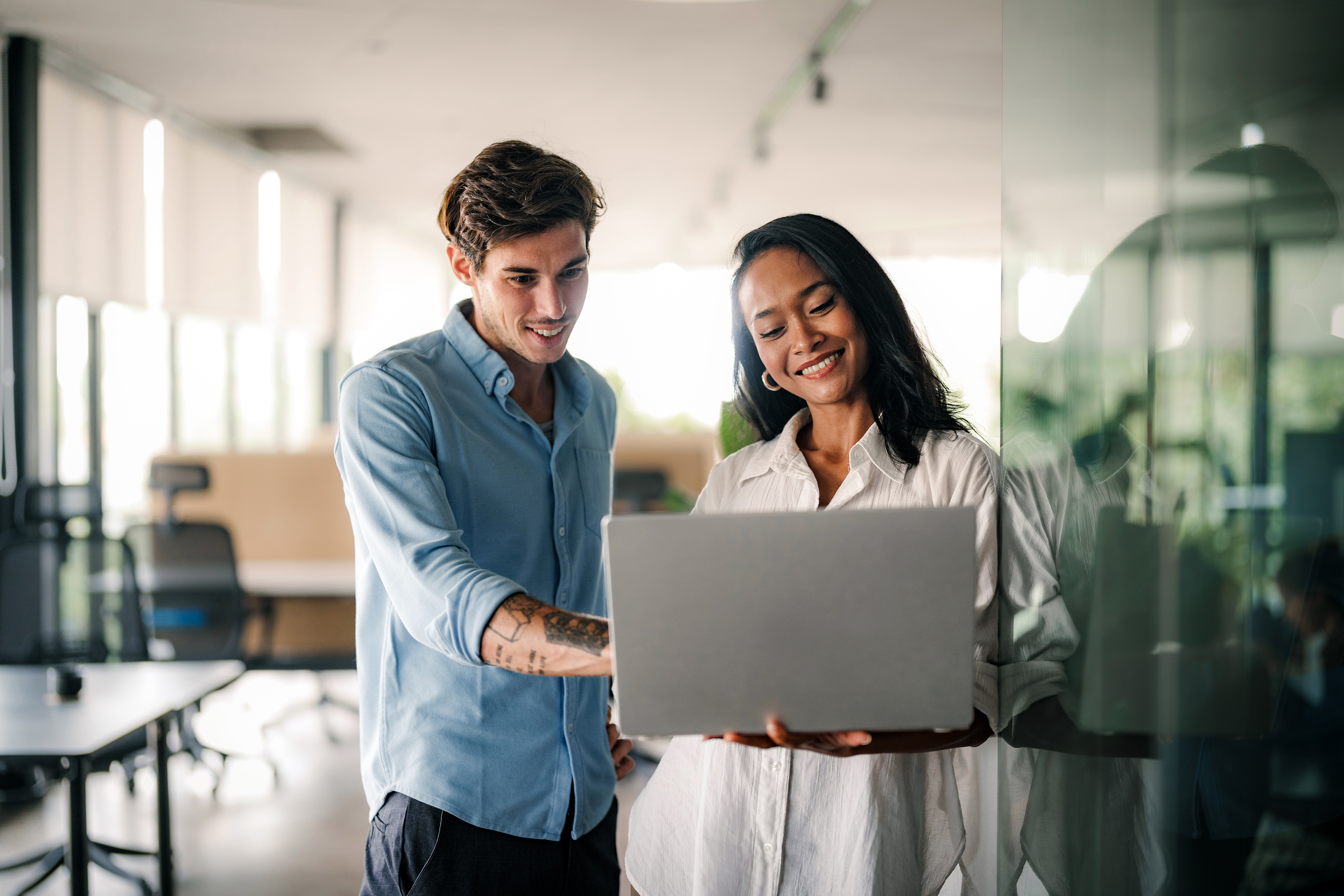 Two employees working together looking at laptop