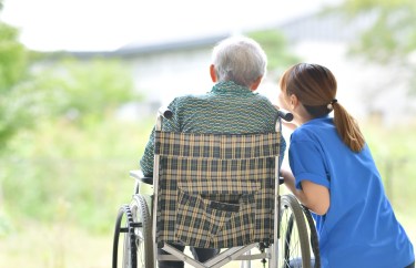 A caretaker talks to a person in a wheelchair.
