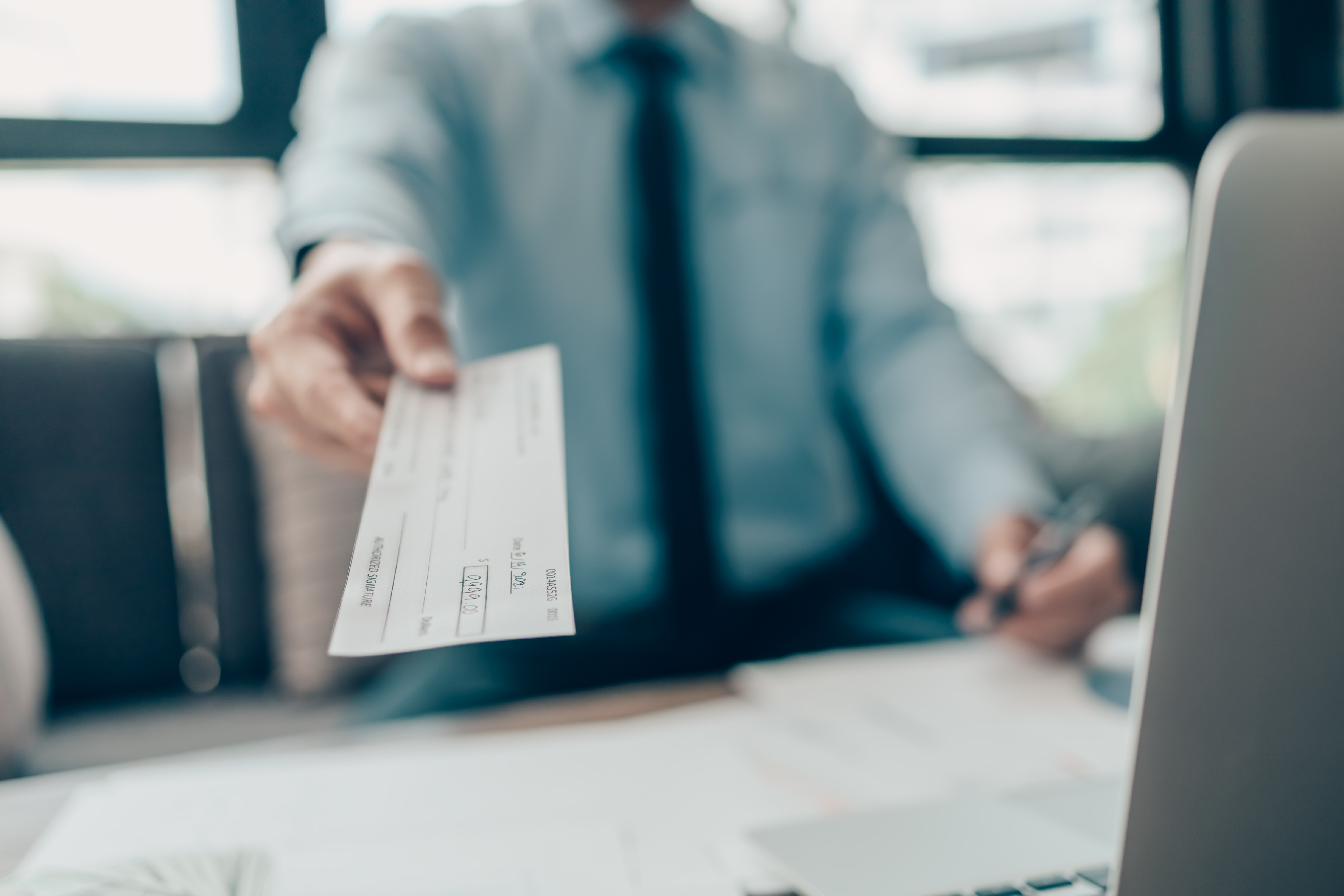 A man hands over a paycheck.