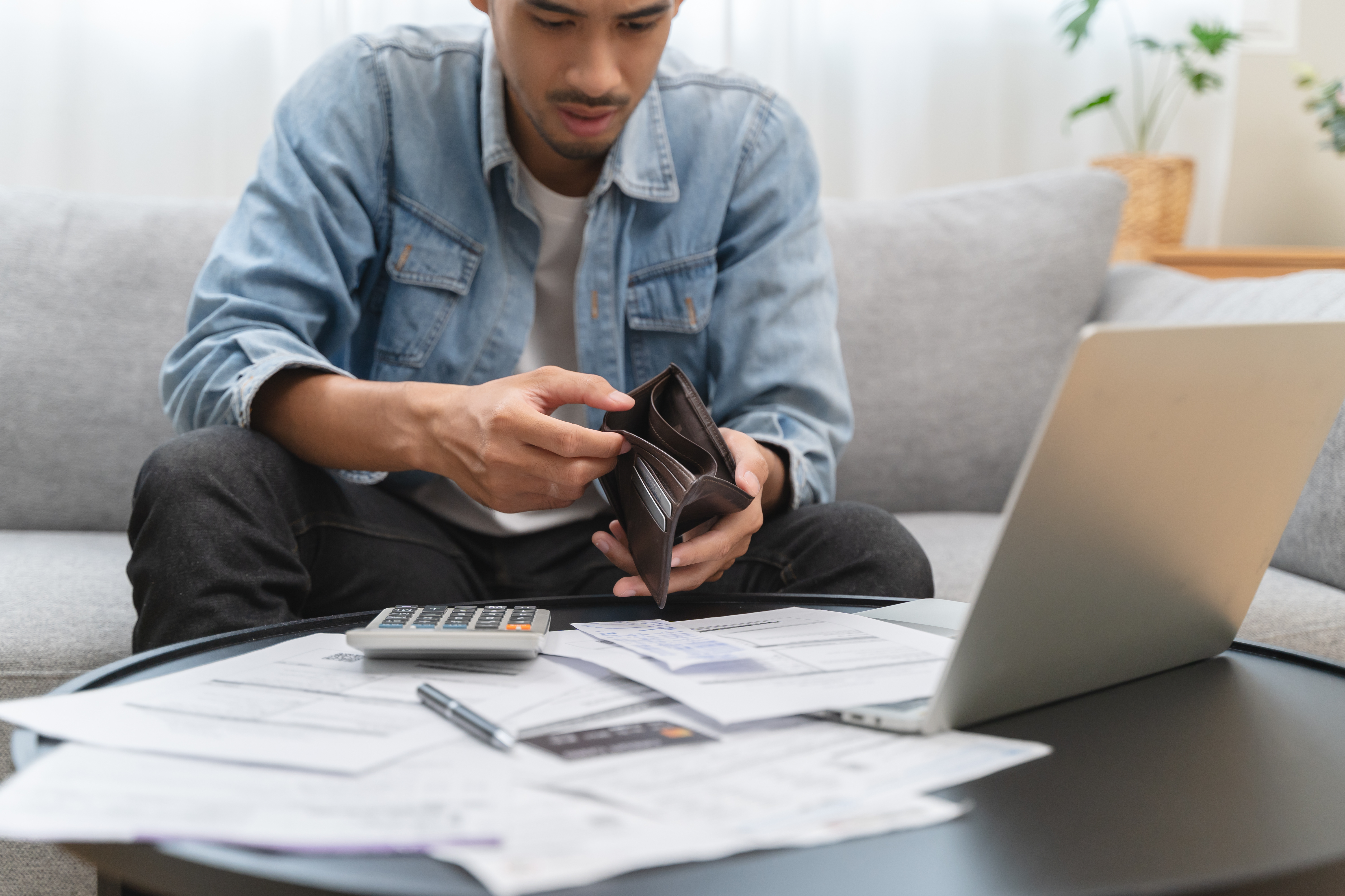 Man looking at empty wallet, money help