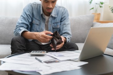 Man looking at empty wallet, money help