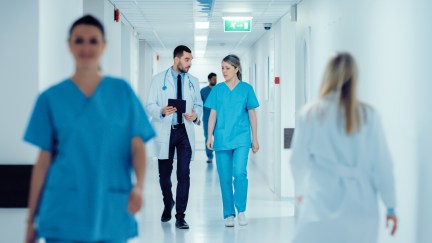 A doctor and a nurse are seen walking down a hallway.