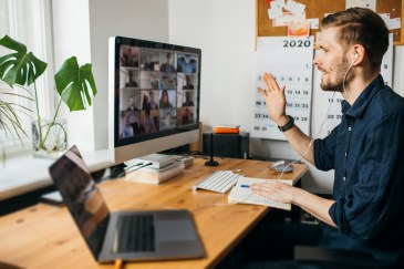A man working from home attends a Zoom meeting.