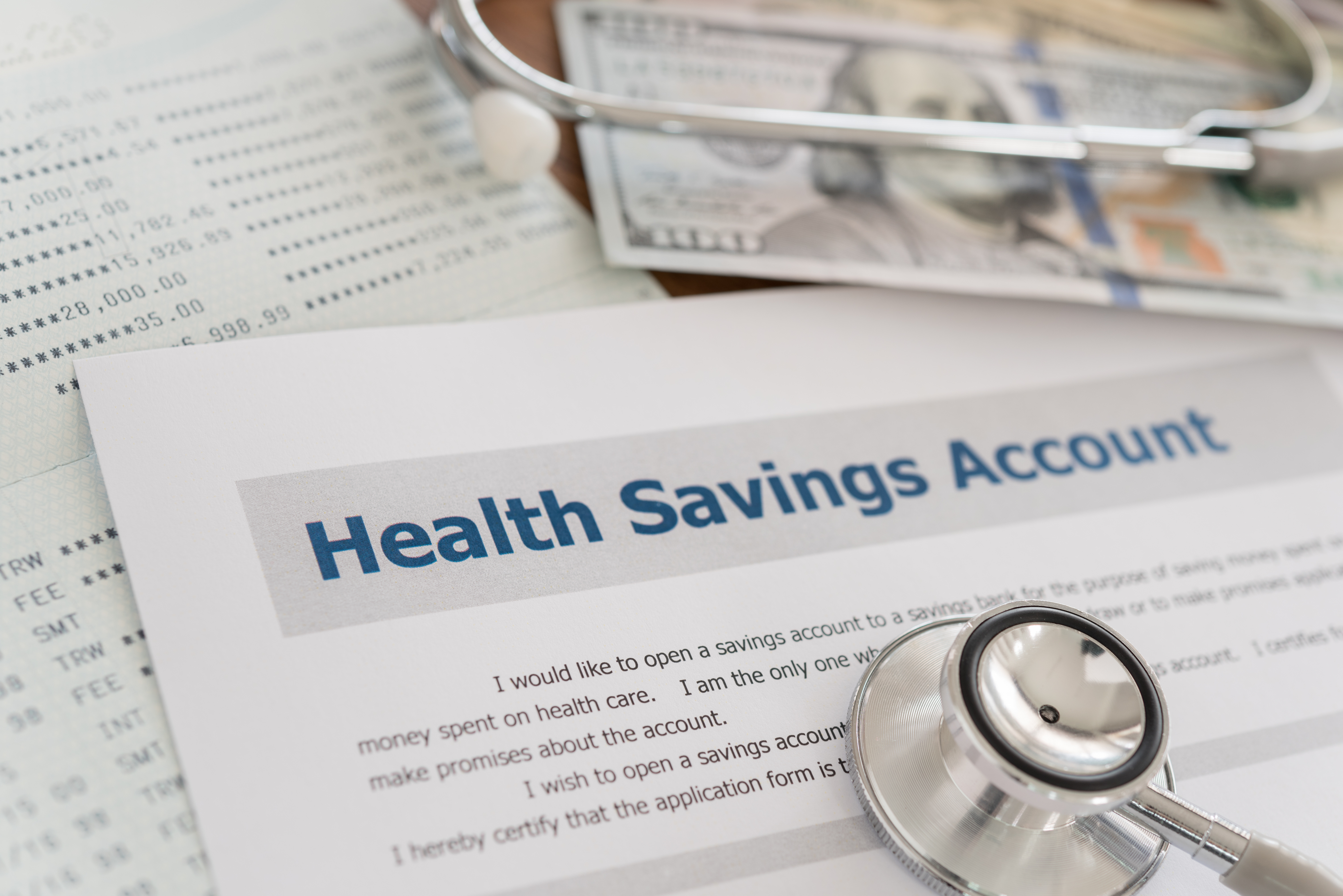 A sheet of paper that says Health Savings Account and a $100 bill.