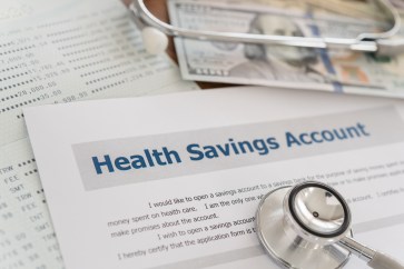 A sheet of paper that says Health Savings Account and a $100 bill.