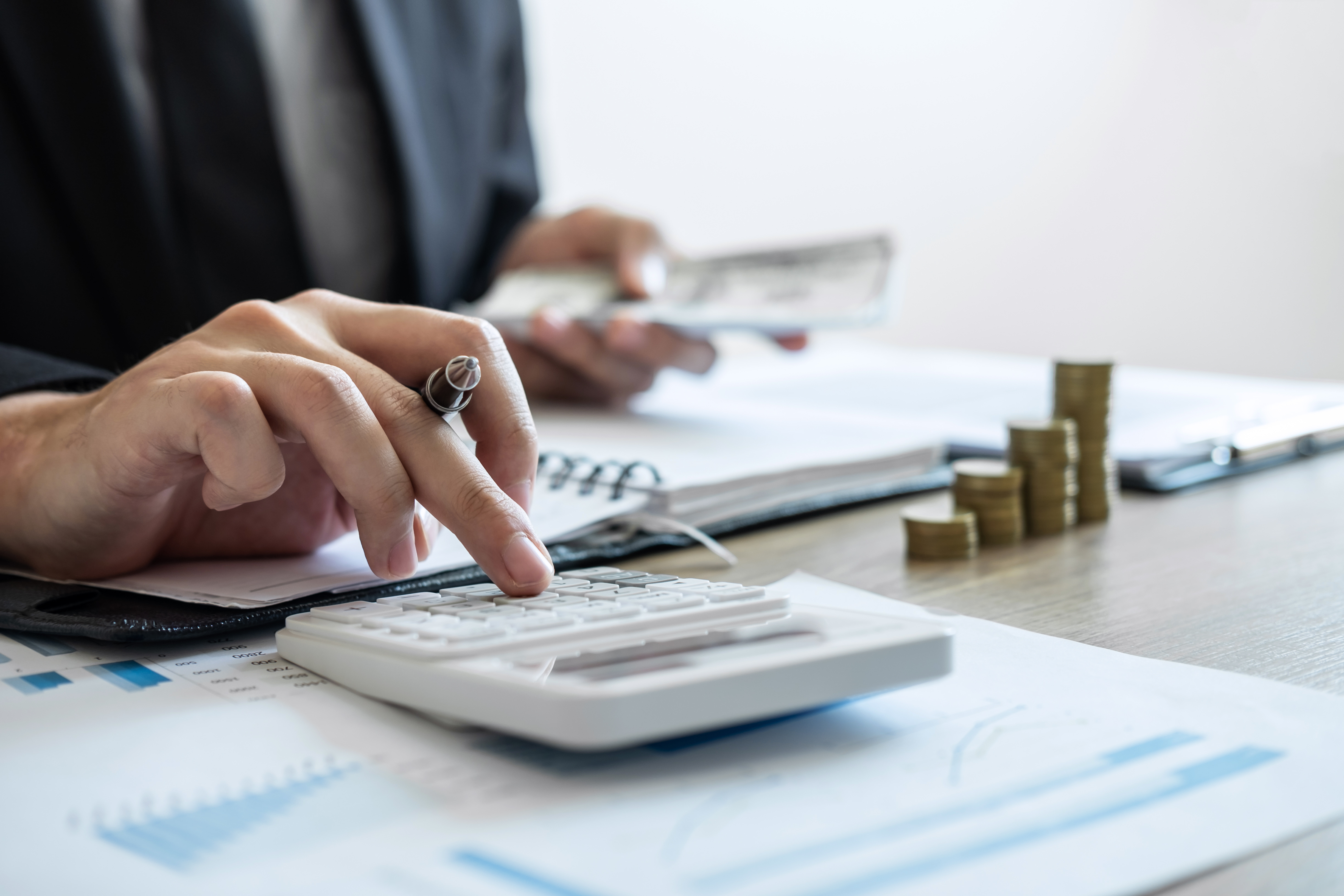 hands pushing buttons on calculator and holding money