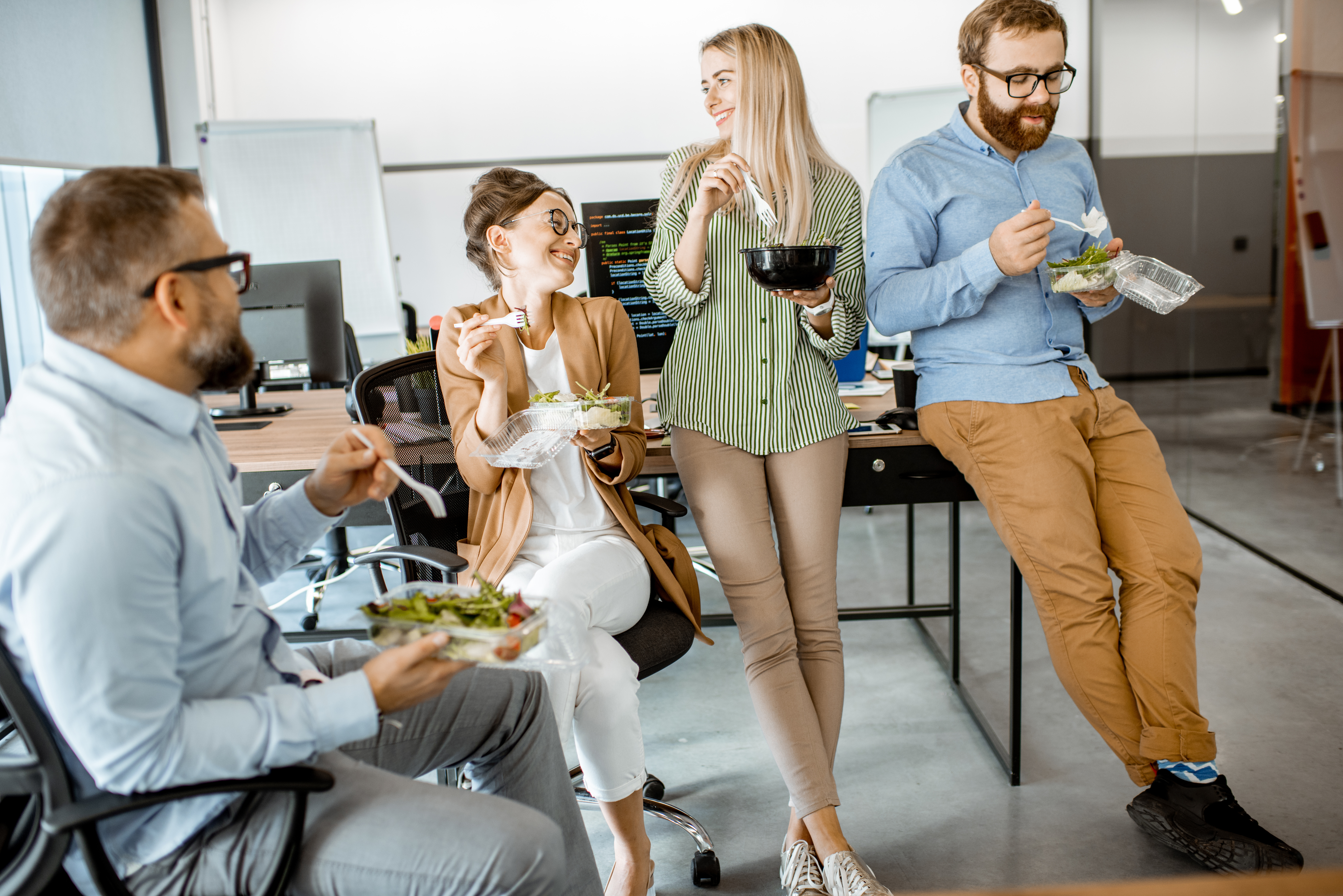 Employees eating, standing and sitting at desk