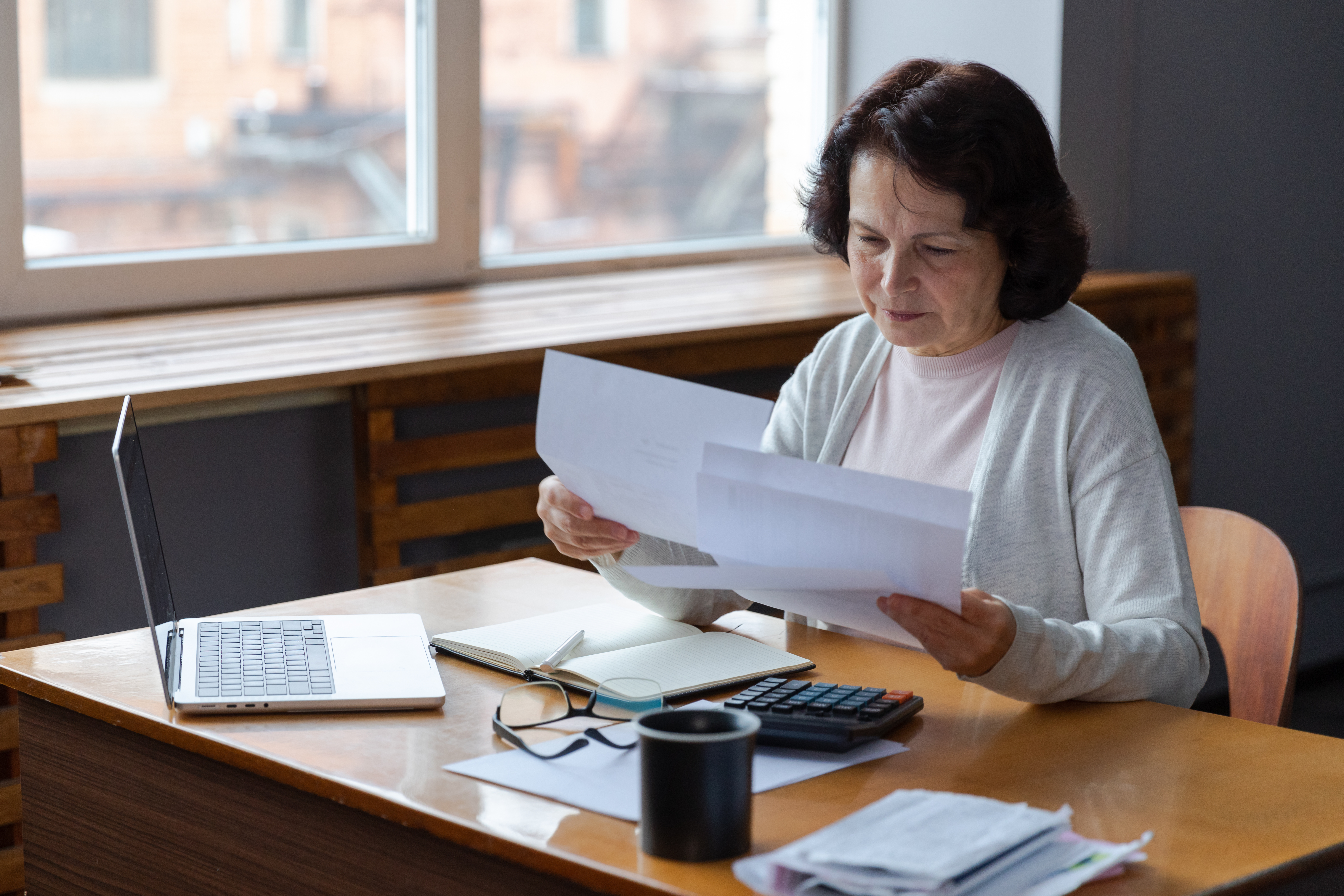 Older woman looking at paperwork, sitting at desk