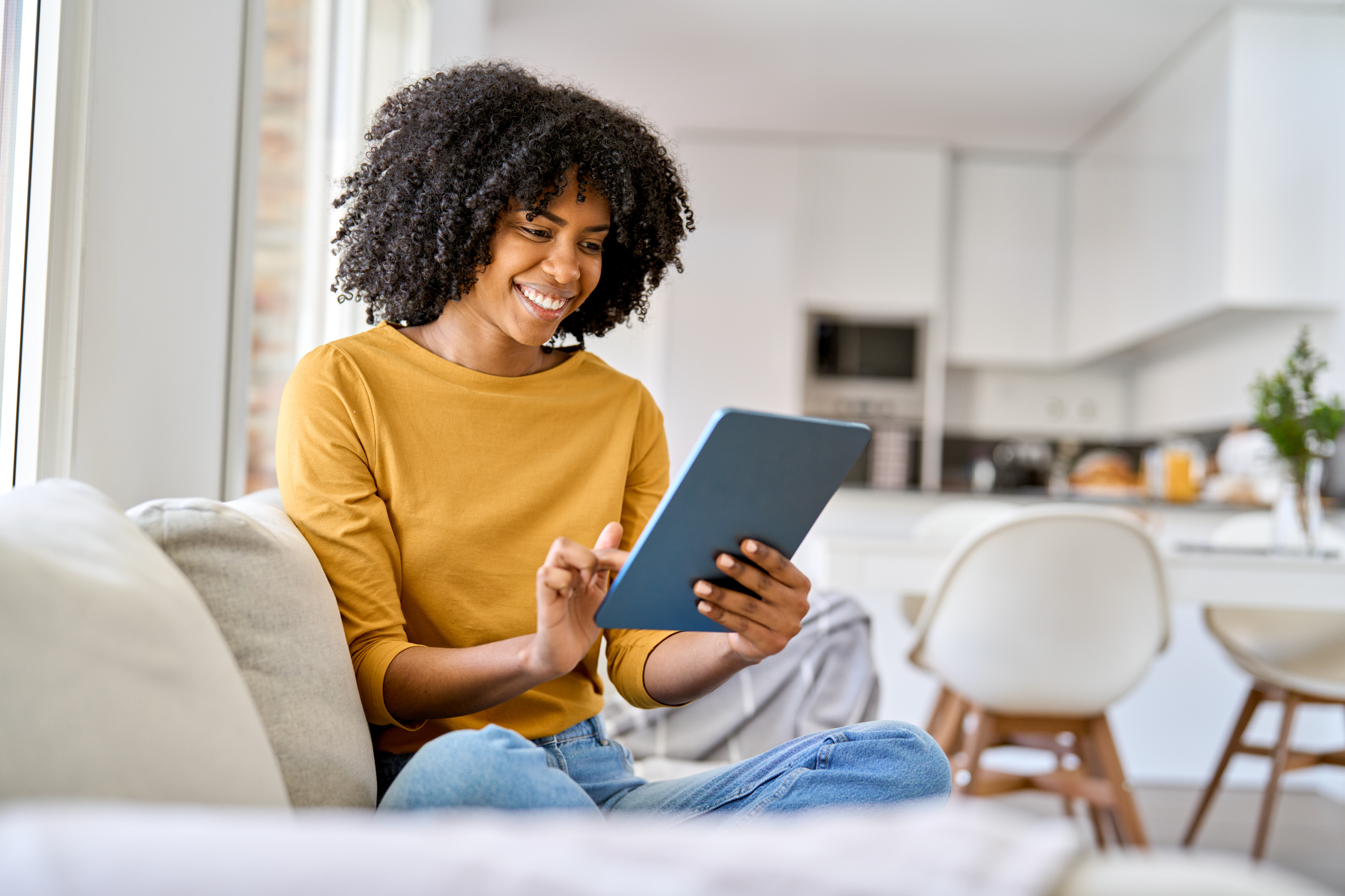 Woman looking at tablet while sitting on couch