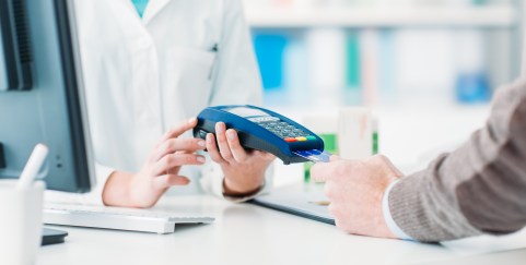 Man's hand holding credit card near machine, paying for doctor visit