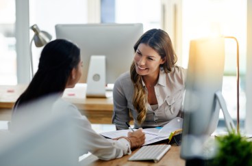 Two women talking to each other in office