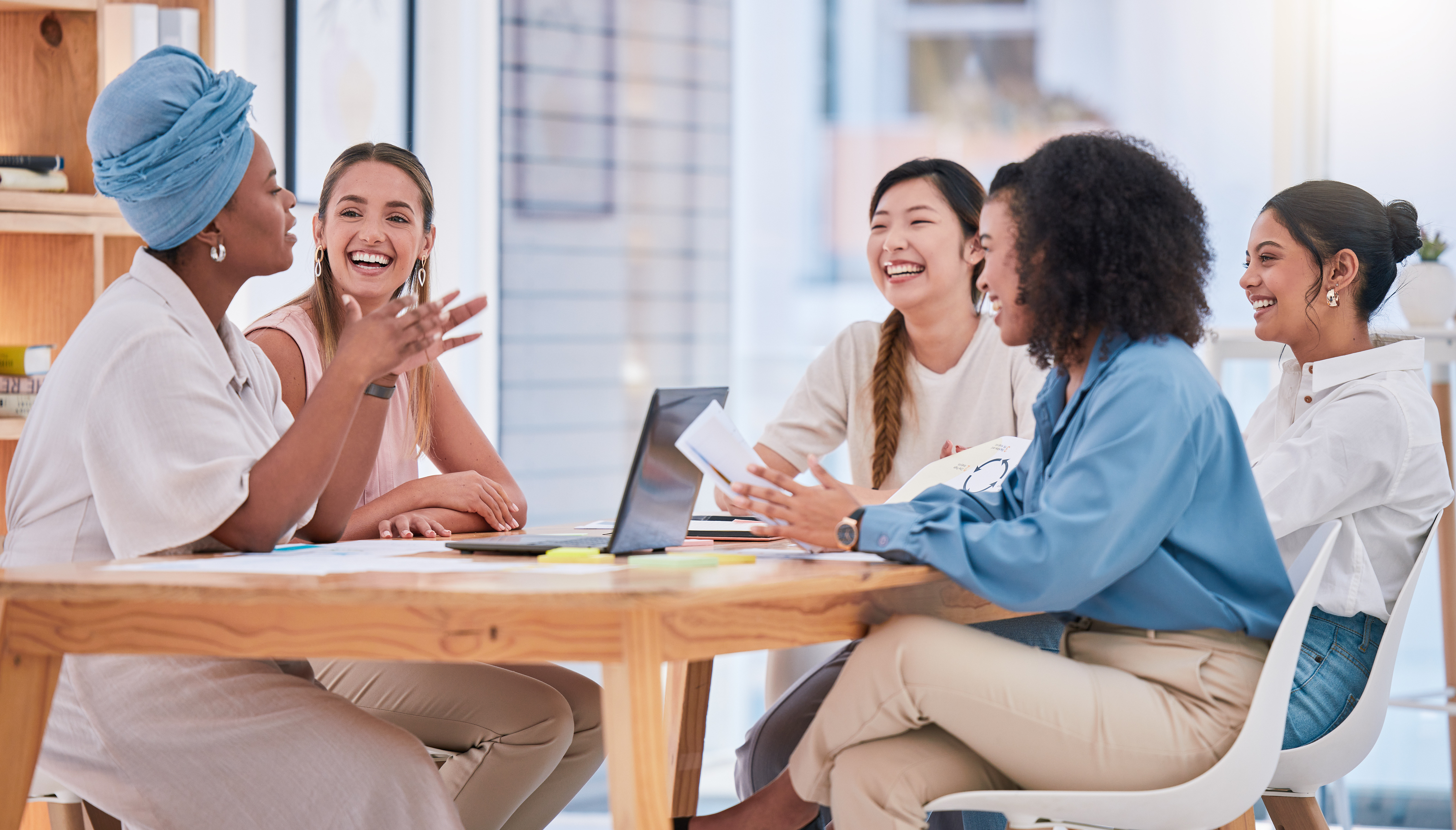 Group of women sitting at table in office working, talking