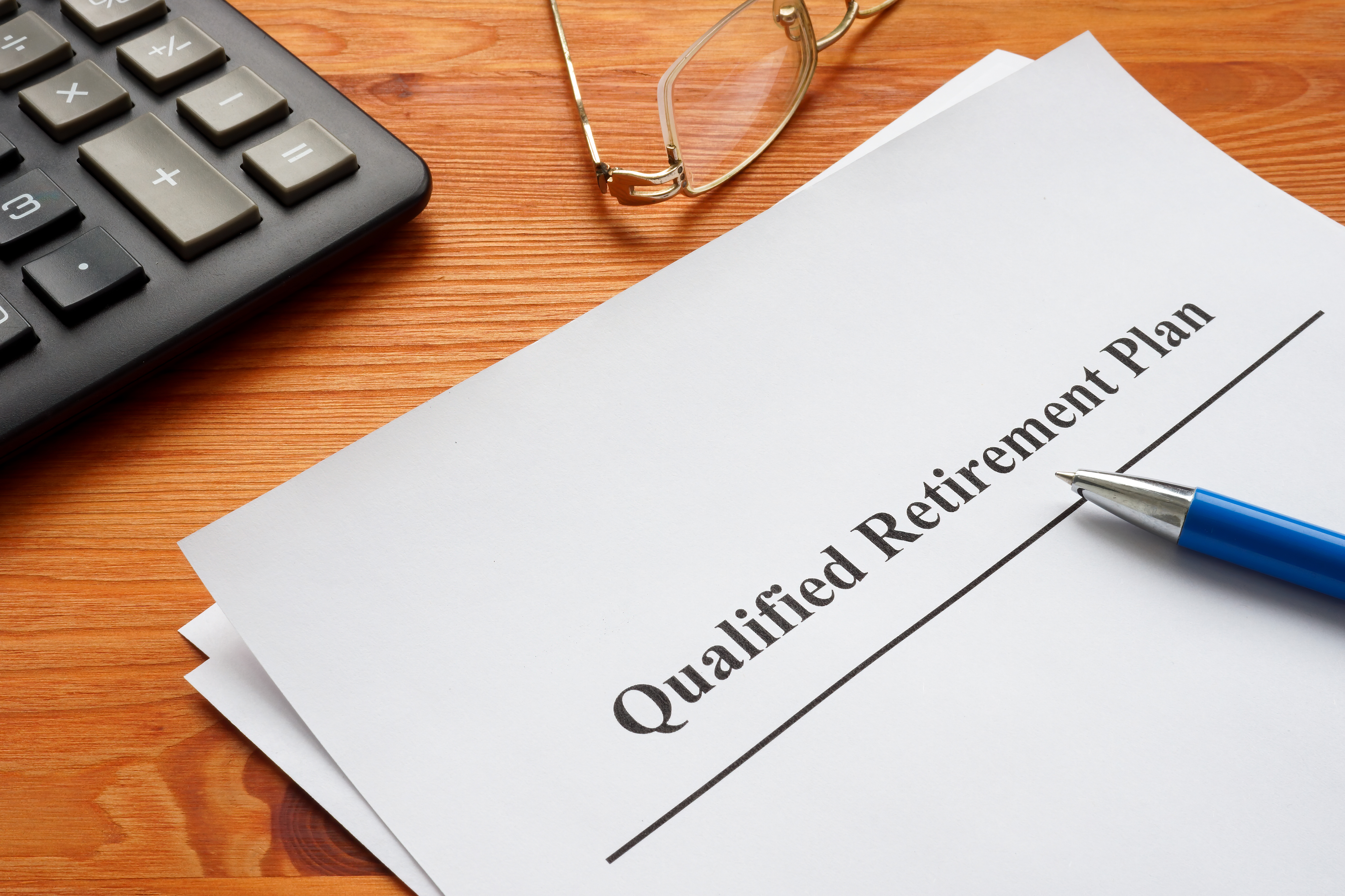 Qualified retirement plan, a calculator and glasses.