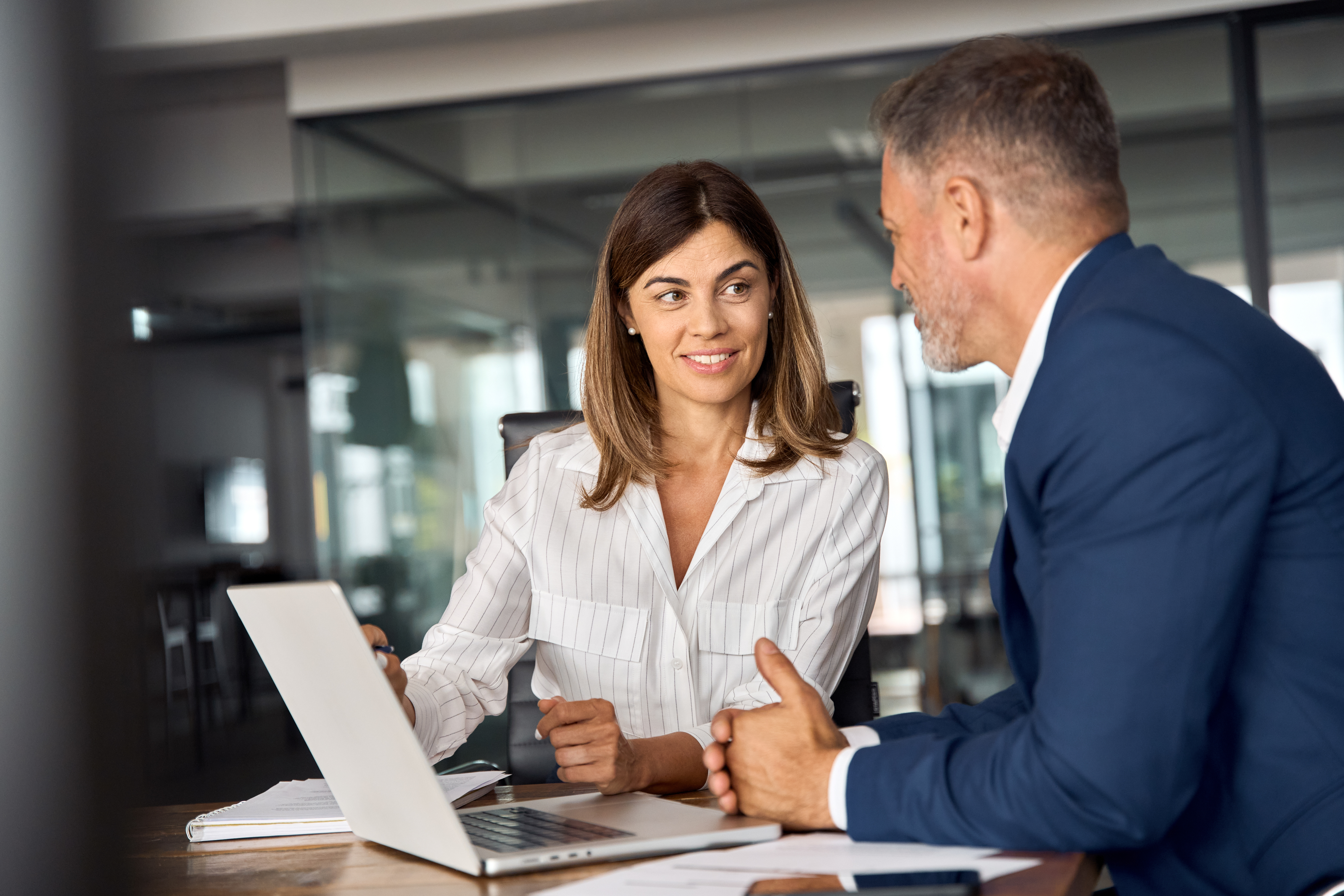 Female and male employee working together on laptop, sitting at table