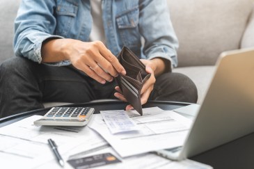 Man holding empty wallet, paying bills, worried about money
