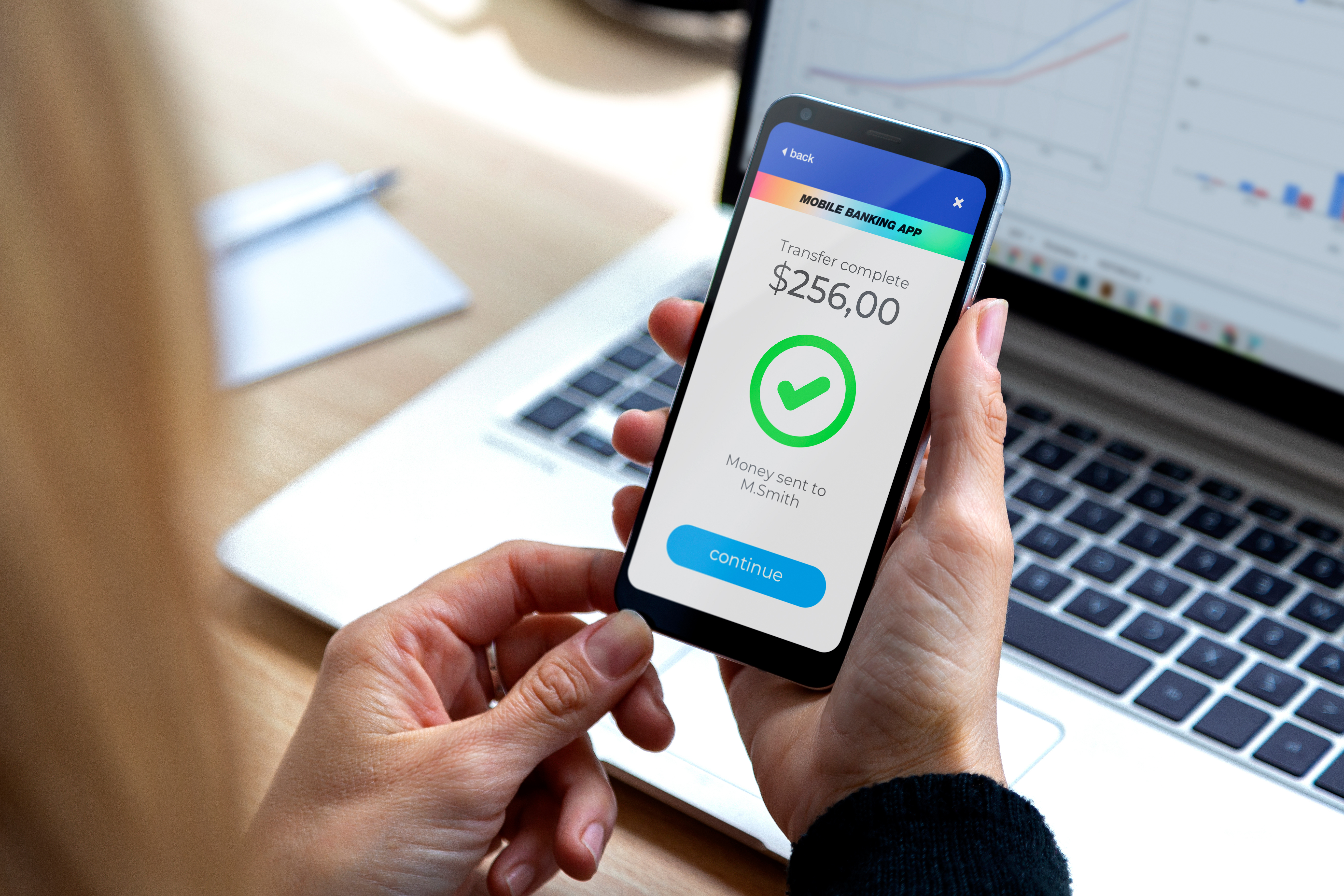 Person holding cell phone with money amount and check symbol