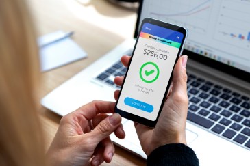 Person holding cell phone with money amount and check symbol