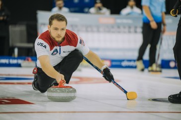 A young man competes in a curling competition.