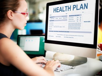 Woman looking at computer filling out healthcare plan information