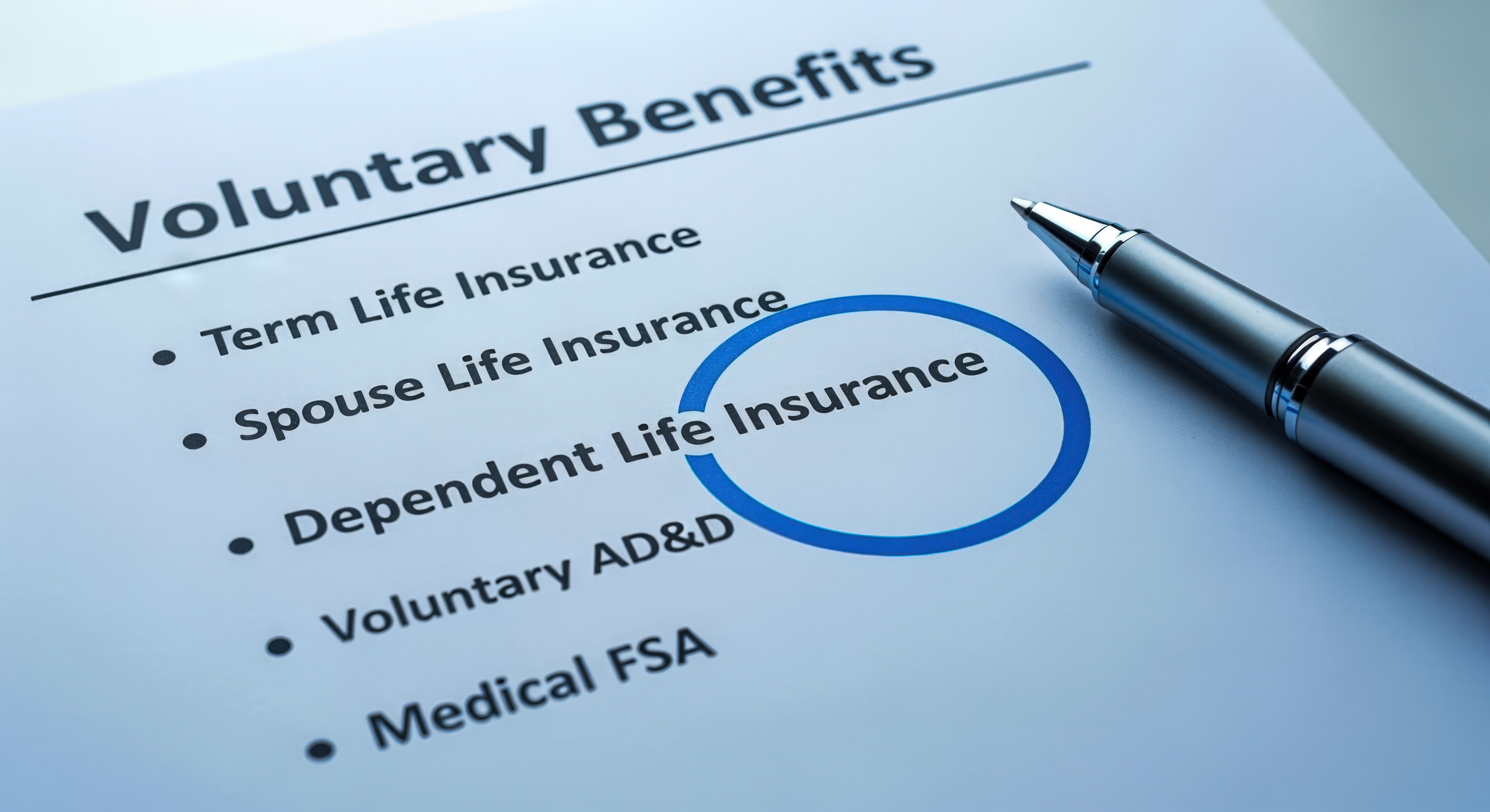 Voluntary benefits form with pen highlighting spouse life insurance option for employee enrollment.