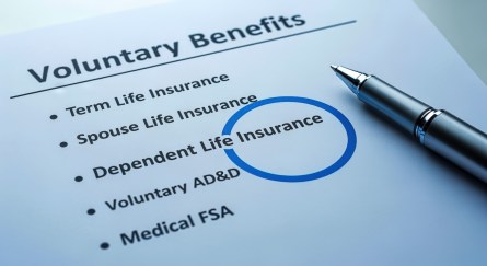 Voluntary benefits form with pen highlighting spouse life insurance option for employee enrollment.