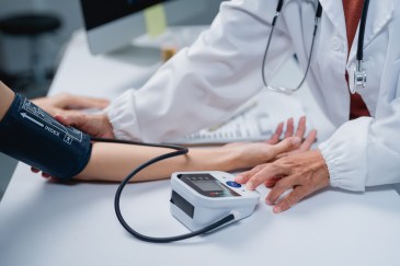 Doctor checking patient blood pressure measuring hypertension.