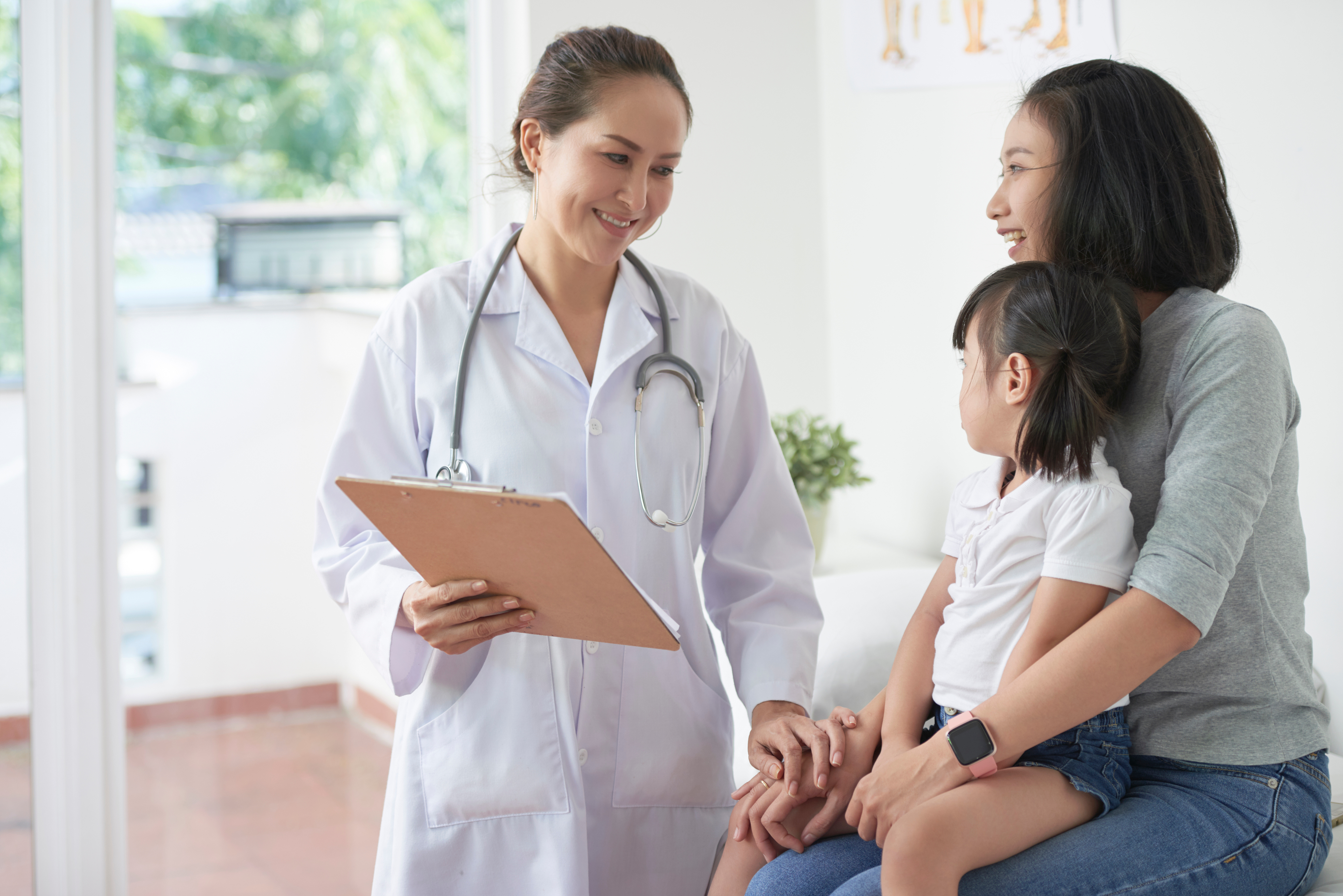Mother holding daughter in pediatrician's office