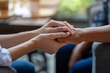 Hand holding older person's hand, comforting