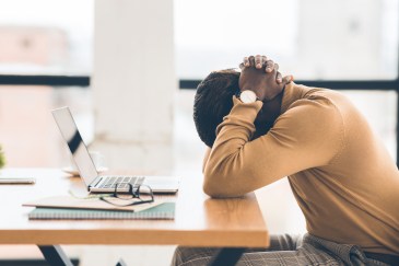 Employee with head on desk, sad, stressed