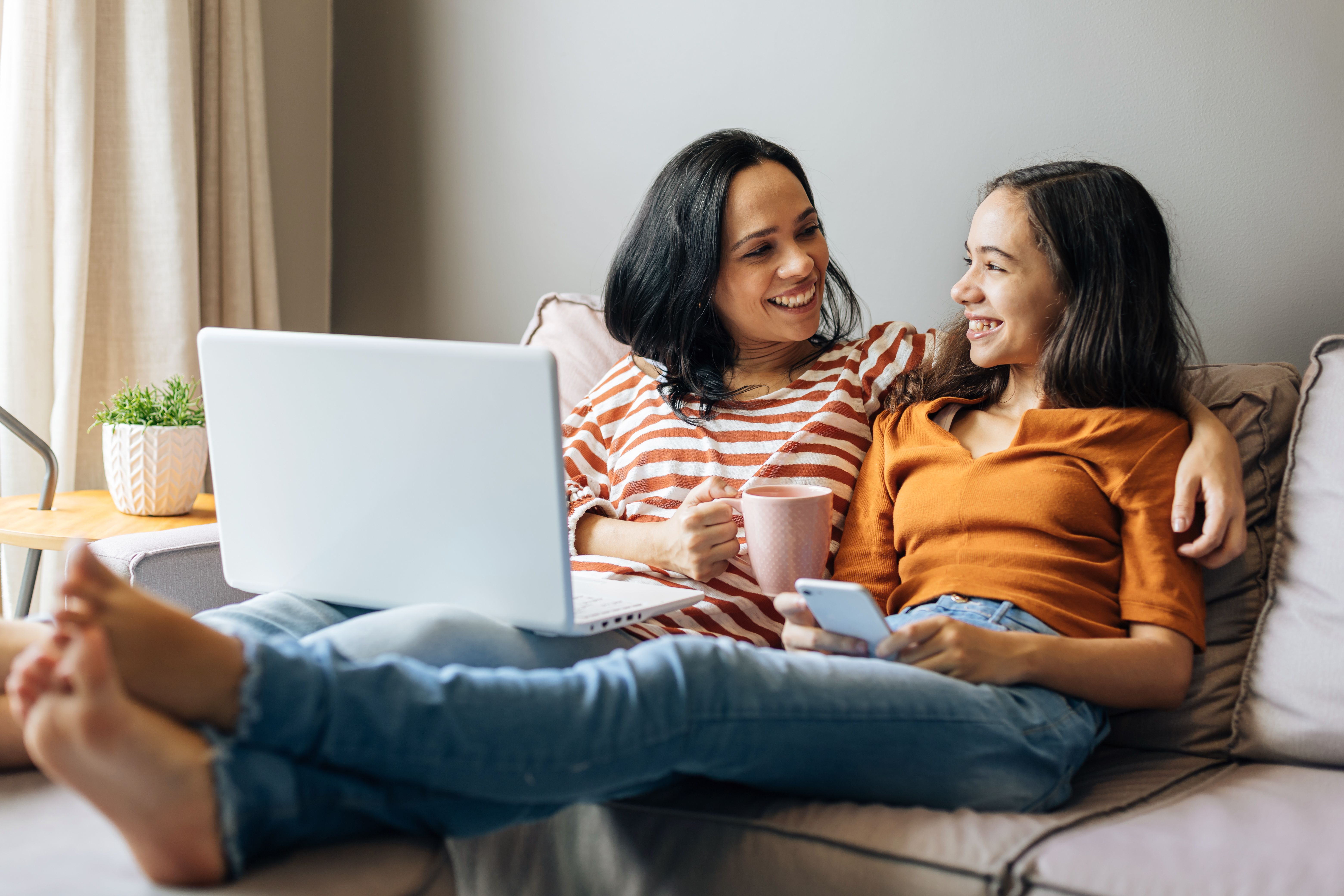 Mom and daughter sitting on couch talking, smiling