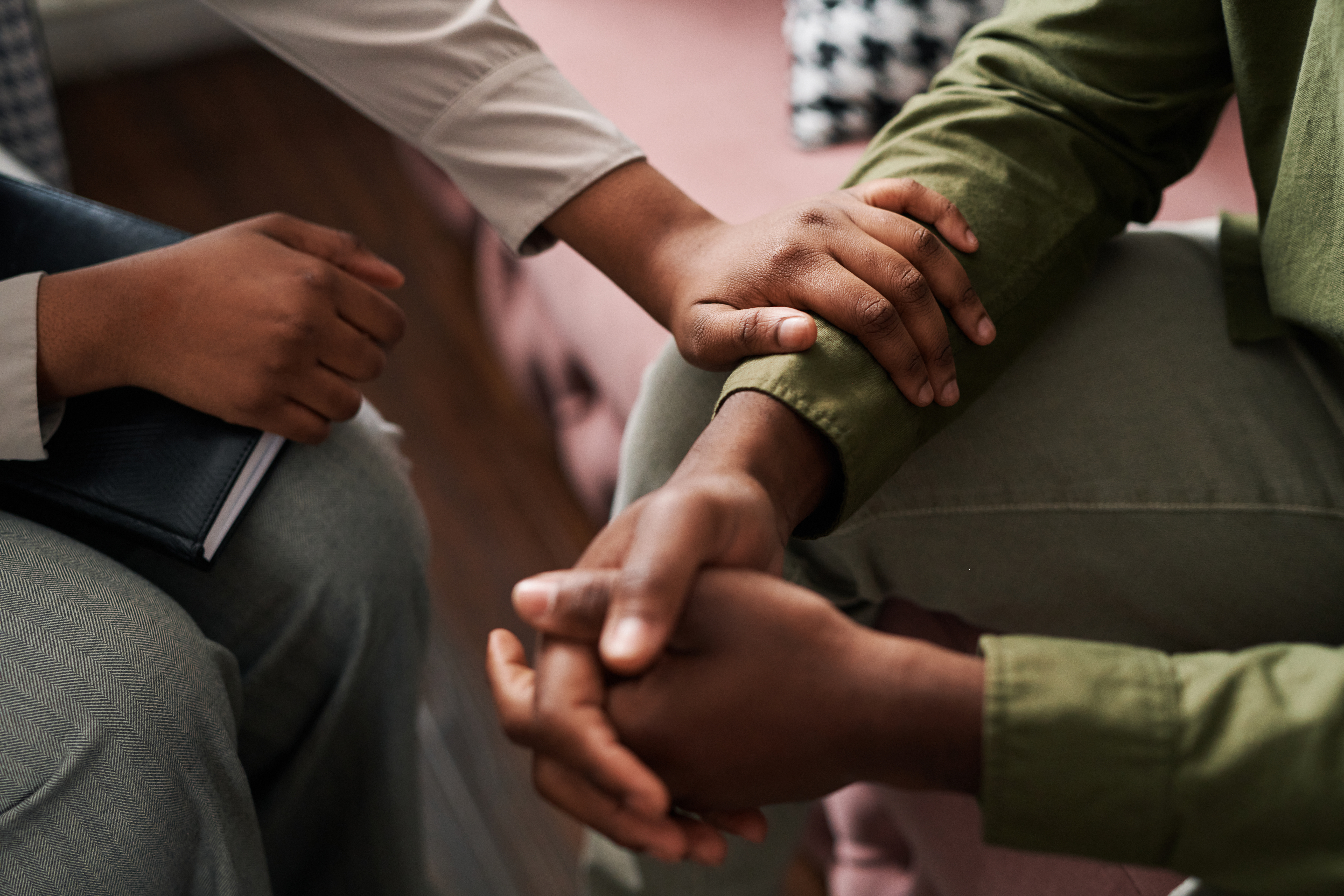 A person sitting down consoling another person.