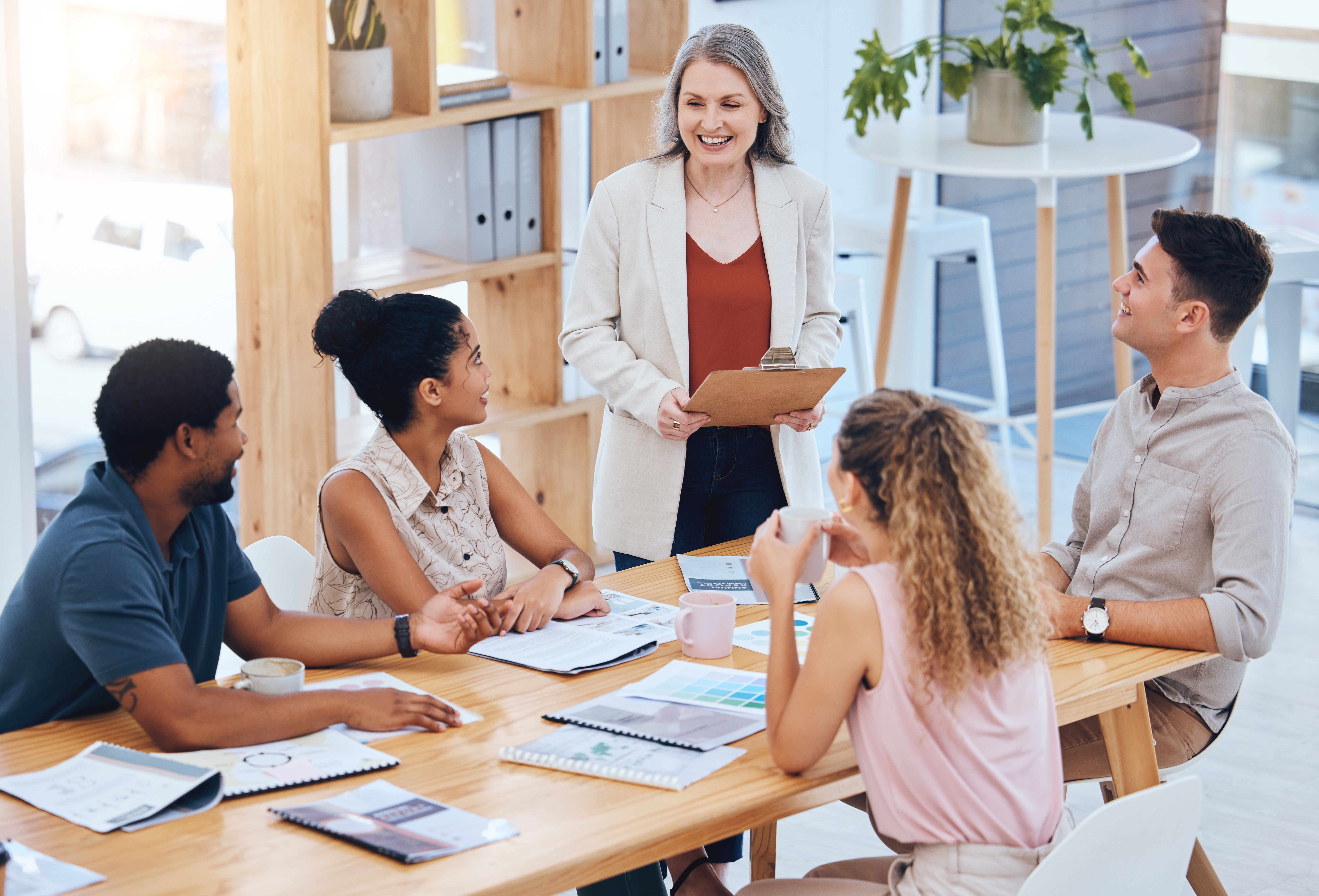 Woman standing, speaking to seated, listening employees