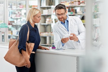 Woman standing at pharmacy counter talking to pharmacist