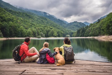 Family with dog looking out over lake and mountains
