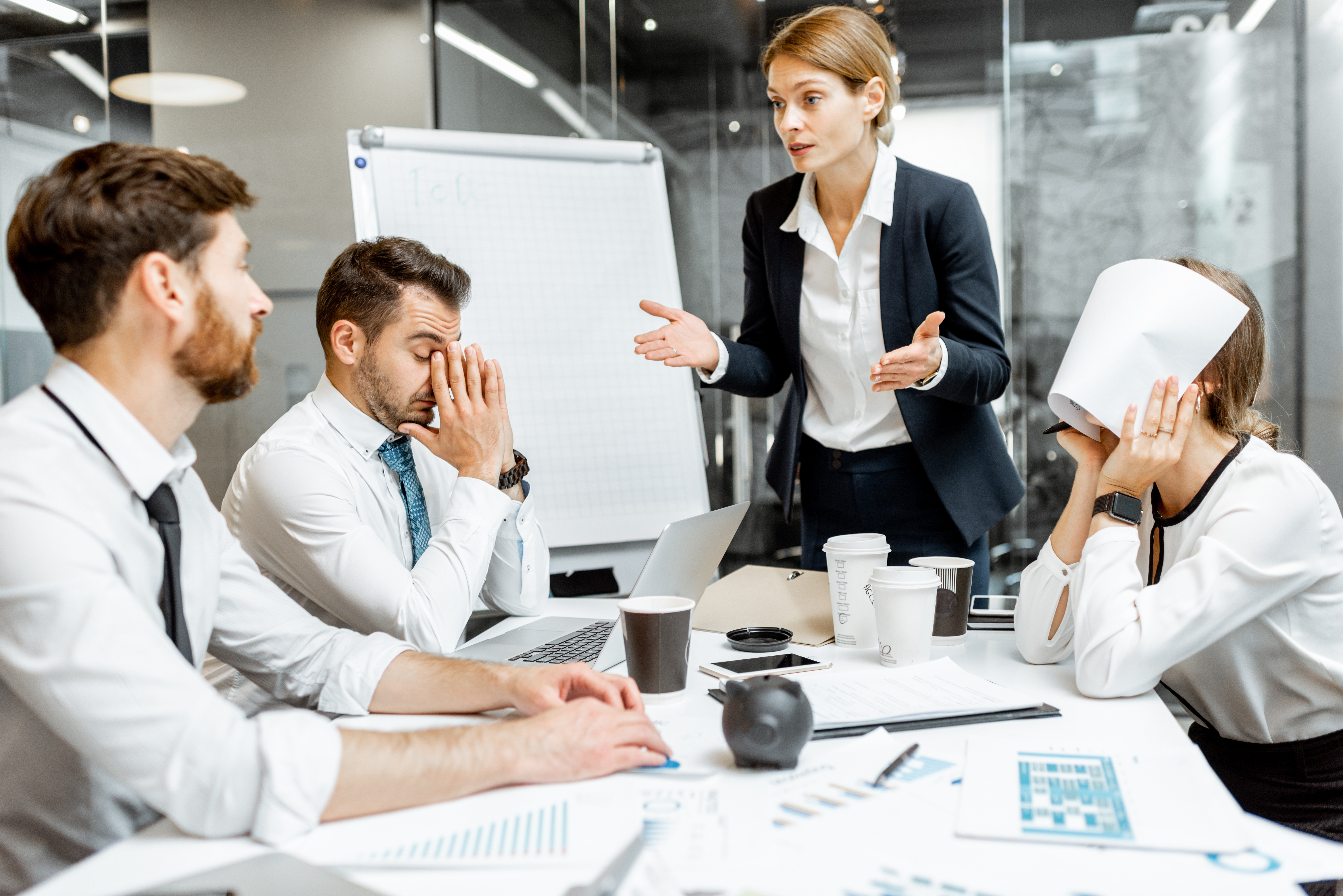 Female employees speaking to team, workers stressed, employee with paper over her face, upset