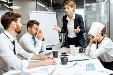 Female employees speaking to team, workers stressed, employee with paper over her face, upset