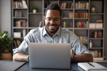 Man working on laptop, smiling
