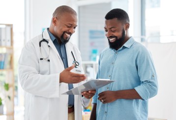 Male doctor talking to male patient, smiling