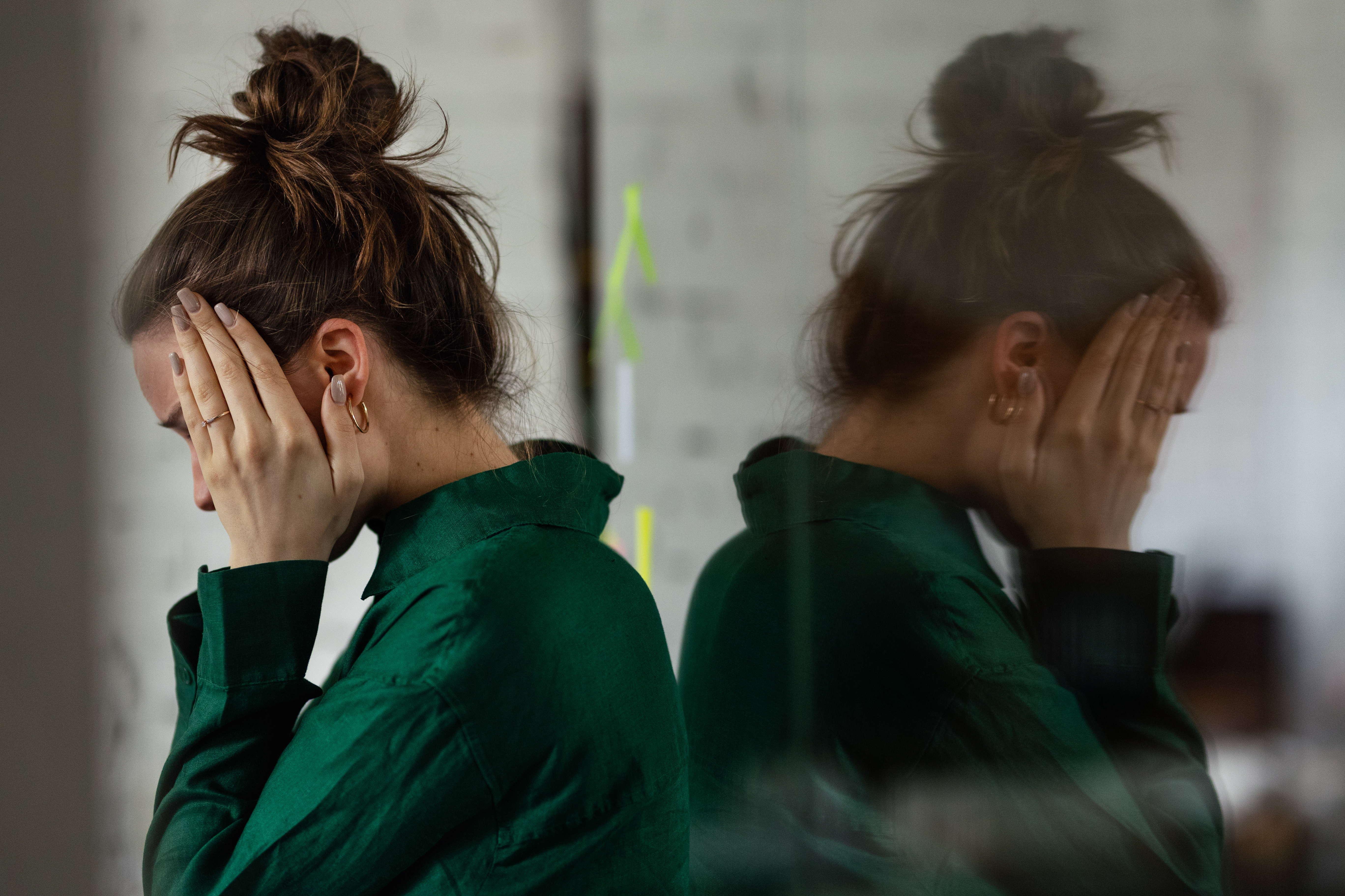 Women holding sides of head, upset, at work