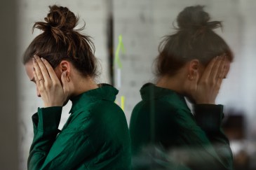 Women holding sides of head, upset, at work