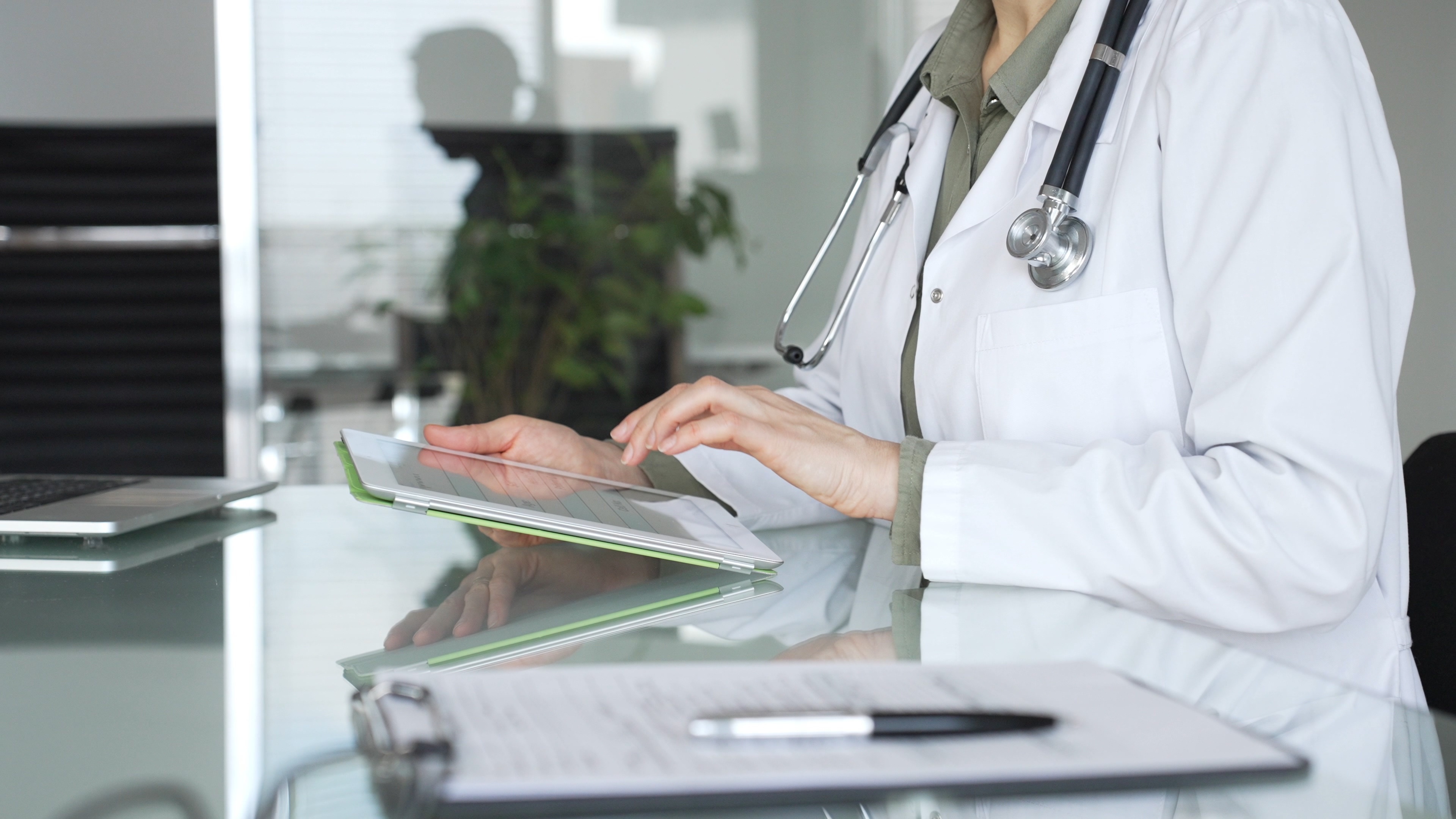 Doctor woman accessing patient data on digital tablet, managing healthcare records in modern medical office. Medicine, health care and science concept.