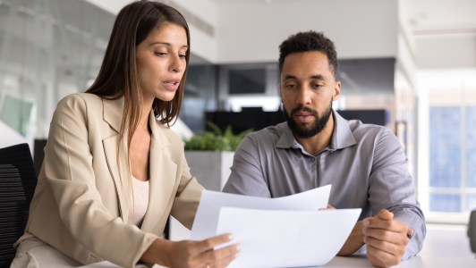 Two employees talking, looking at paperwork, helping